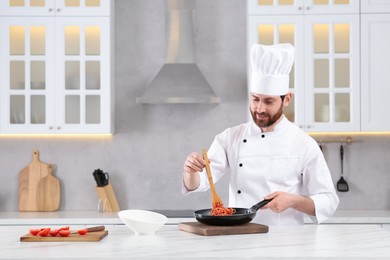 Professional chef with delicious spaghetti at marble table in kitchen