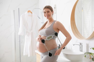 Photo of Young pregnant woman with scales in bathroom