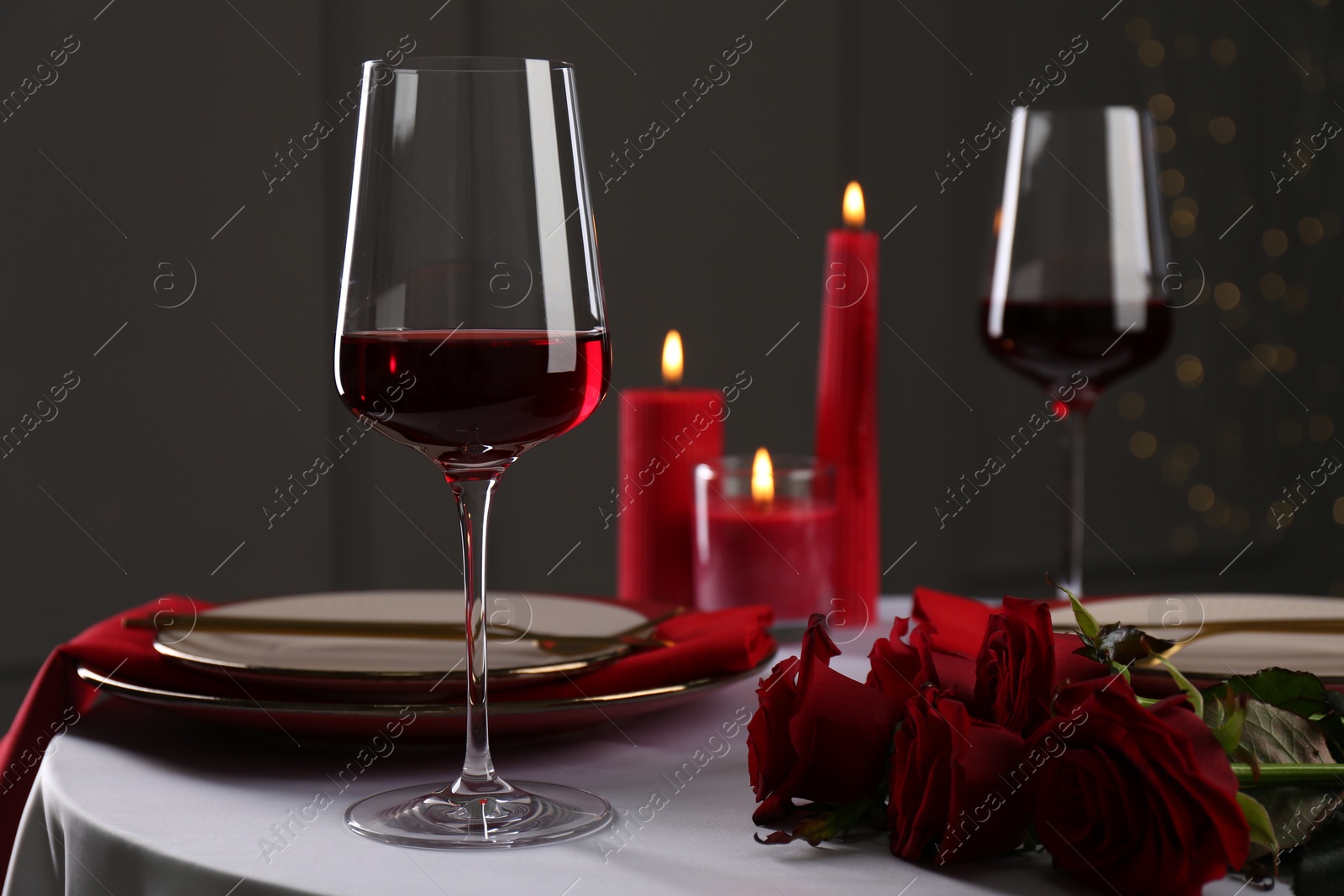 Photo of Place setting with roses and candles on white table, closeup. Romantic dinner