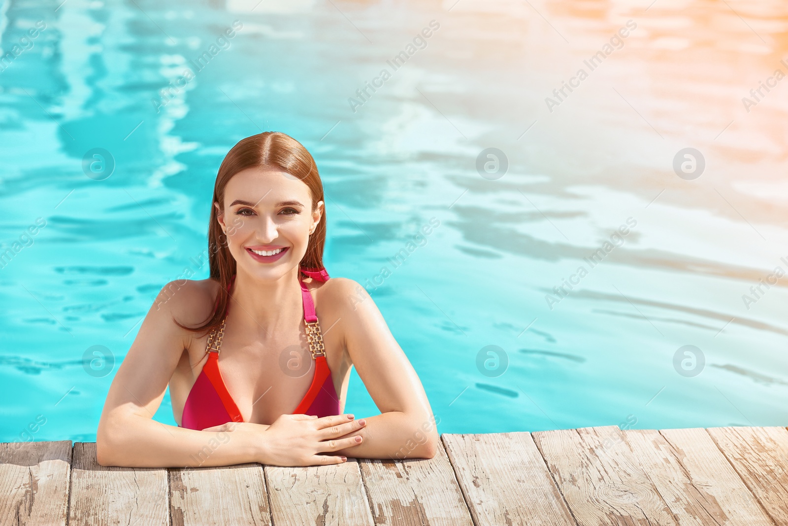 Image of Beautiful young woman in swimming pool on sunny day