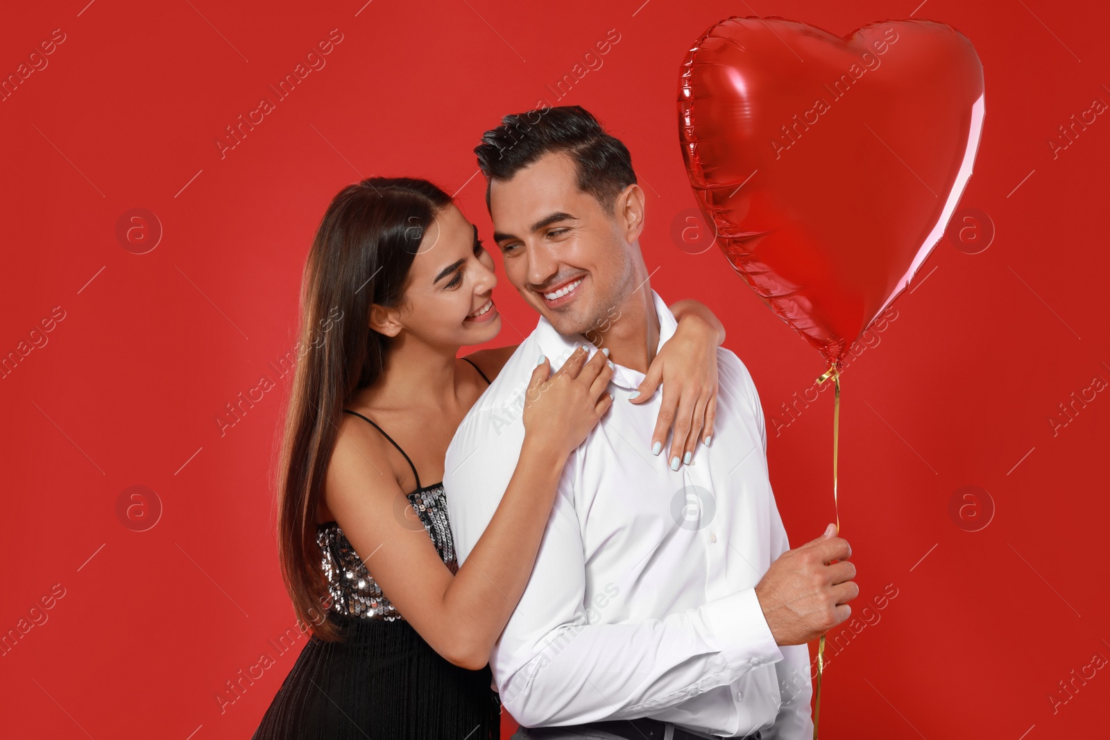 Photo of Beautiful couple with heart shaped balloon on red background