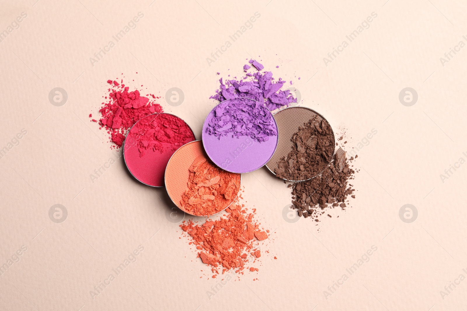 Photo of Different crushed eye shadows on beige background, flat lay