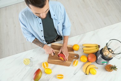 Photo of Man preparing ingredients for tasty smoothie at white marble table, above view