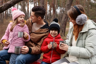 Photo of Happy family with hot drinks spending time together in forest