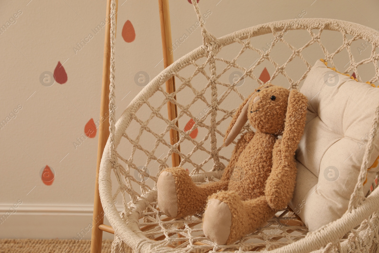 Photo of Swing with toy bunny indoors. Interior design
