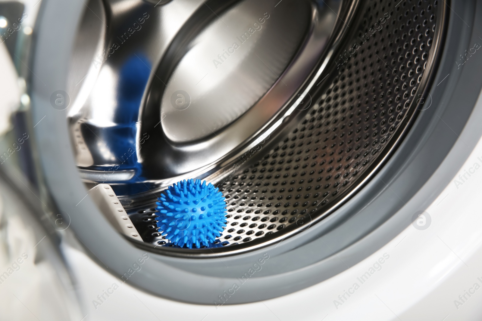 Photo of Blue dryer ball in washing machine drum, closeup