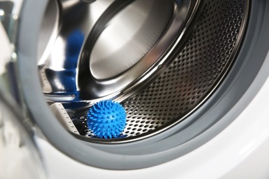 Photo of Blue dryer ball in washing machine drum, closeup