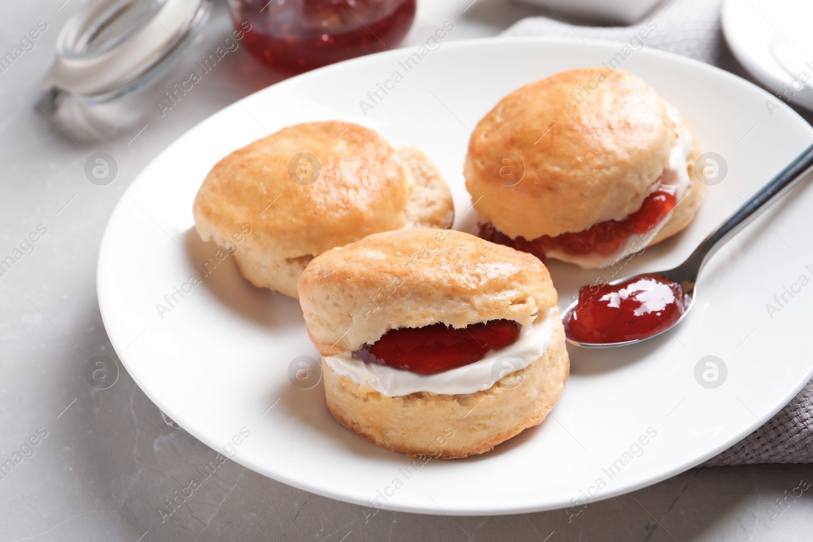 Photo of Tasty scones with clotted cream and jam on table