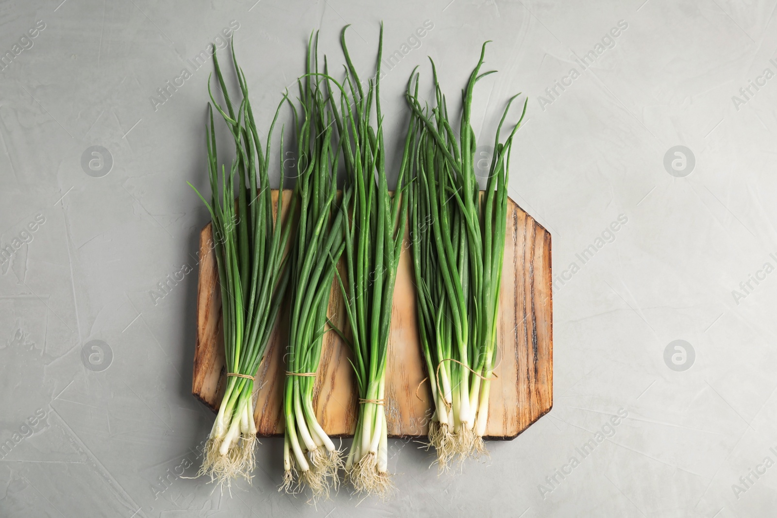 Photo of Fresh green onion on wooden board, top view