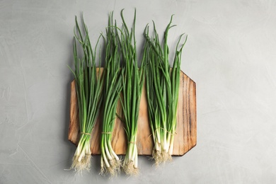 Photo of Fresh green onion on wooden board, top view