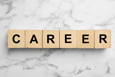 Photo of Wooden cubes with word CAREER on white marble background, flat lay