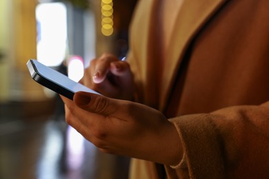 Photo of Woman using smartphone on night city street, closeup