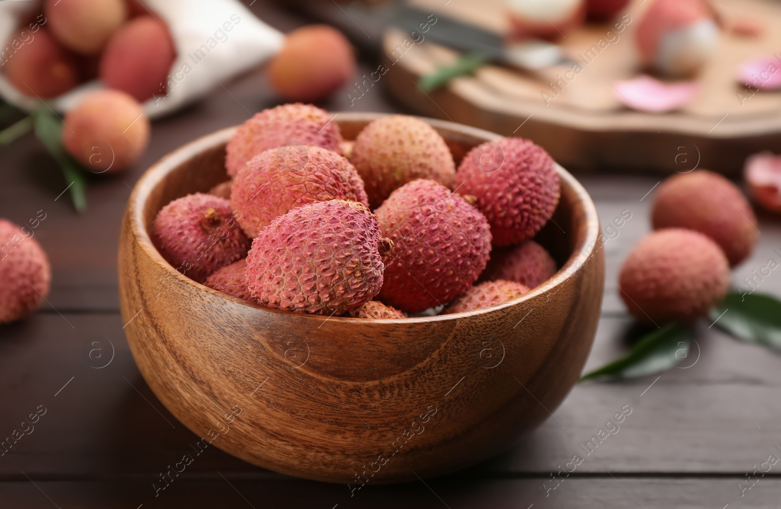 Photo of Fresh ripe lychee fruits in bowl on wooden table