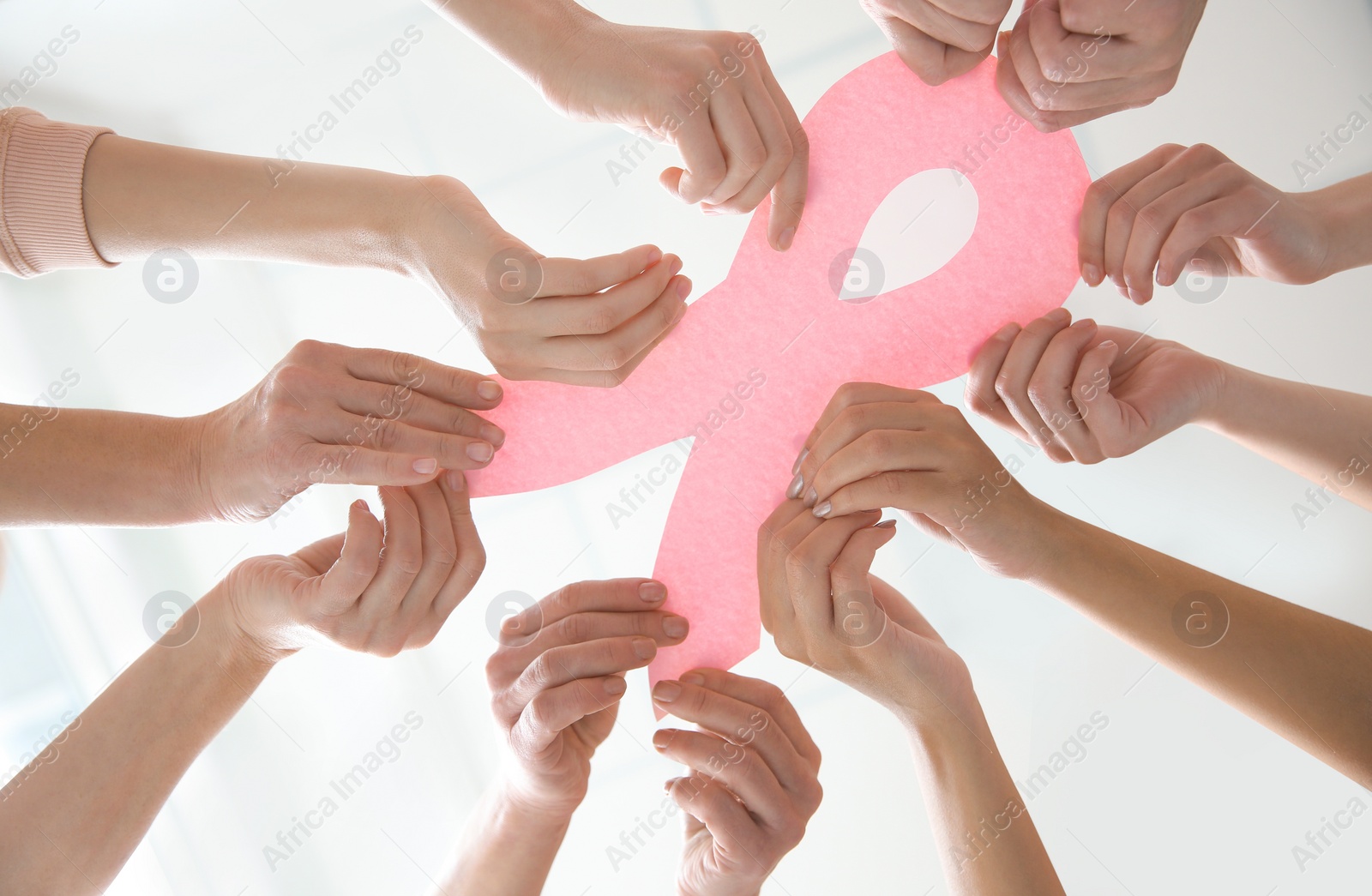 Photo of Women holding pink paper ribbon, bottom view. Breast cancer awareness concept