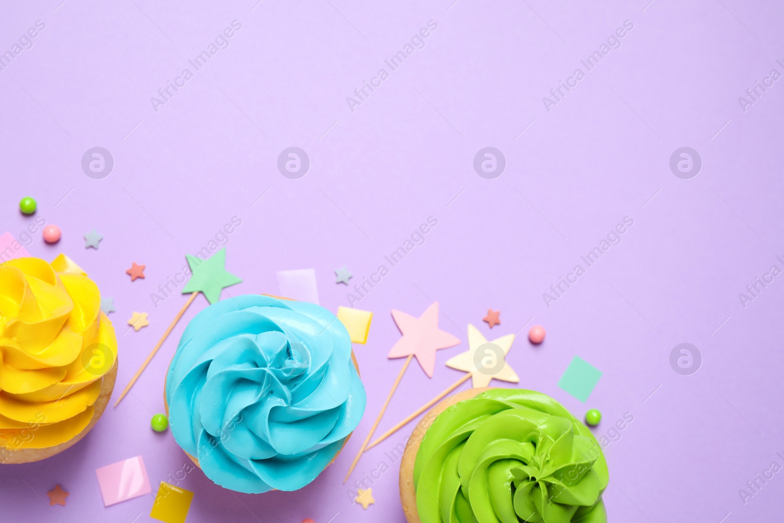 Photo of Colorful birthday cupcakes on lilac background, flat lay. Space for text