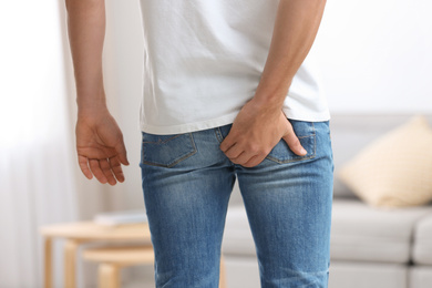 Man suffering from hemorrhoid at home, closeup