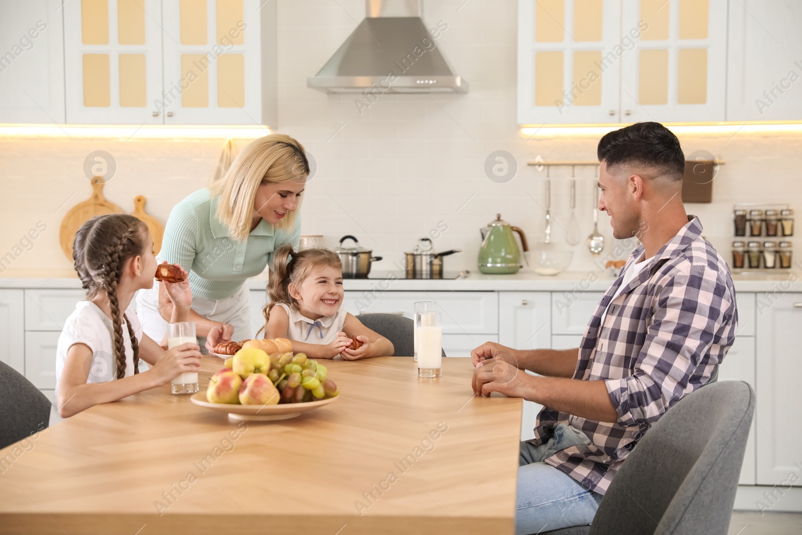 Photo of Happy family eating together at table in modern kitchen