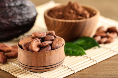 Photo of Wooden bowl of cocoa beans on table