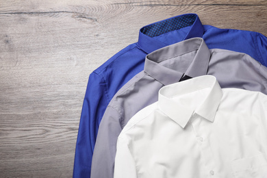 Photo of Stylish shirts on wooden table, flat lay. Dry-cleaning service