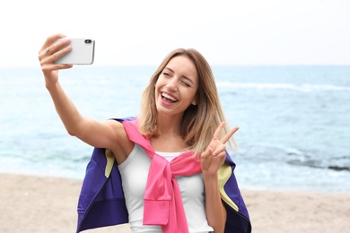 Attractive woman taking selfie on sea coast