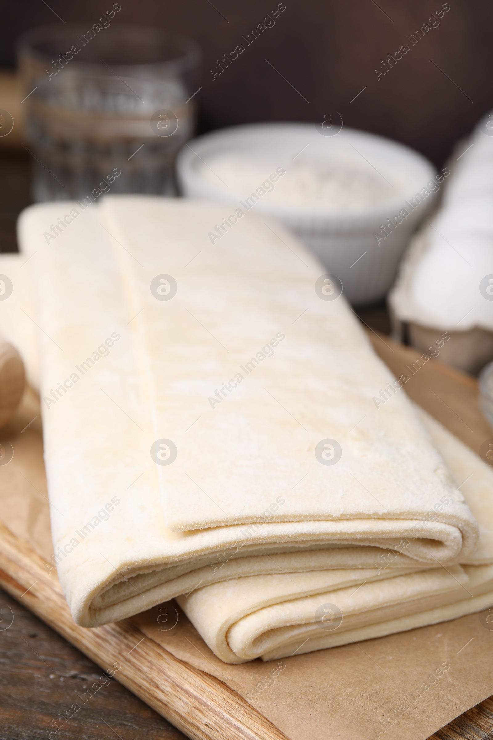 Photo of Raw puff pastry dough on wooden table, closeup