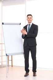 Photo of Young business trainer near flip chart, indoors