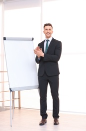 Young business trainer near flip chart, indoors