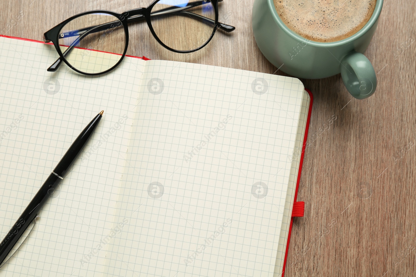 Photo of Blank notebook, cup of coffee and glasses on wooden table, flat lay. Space for text