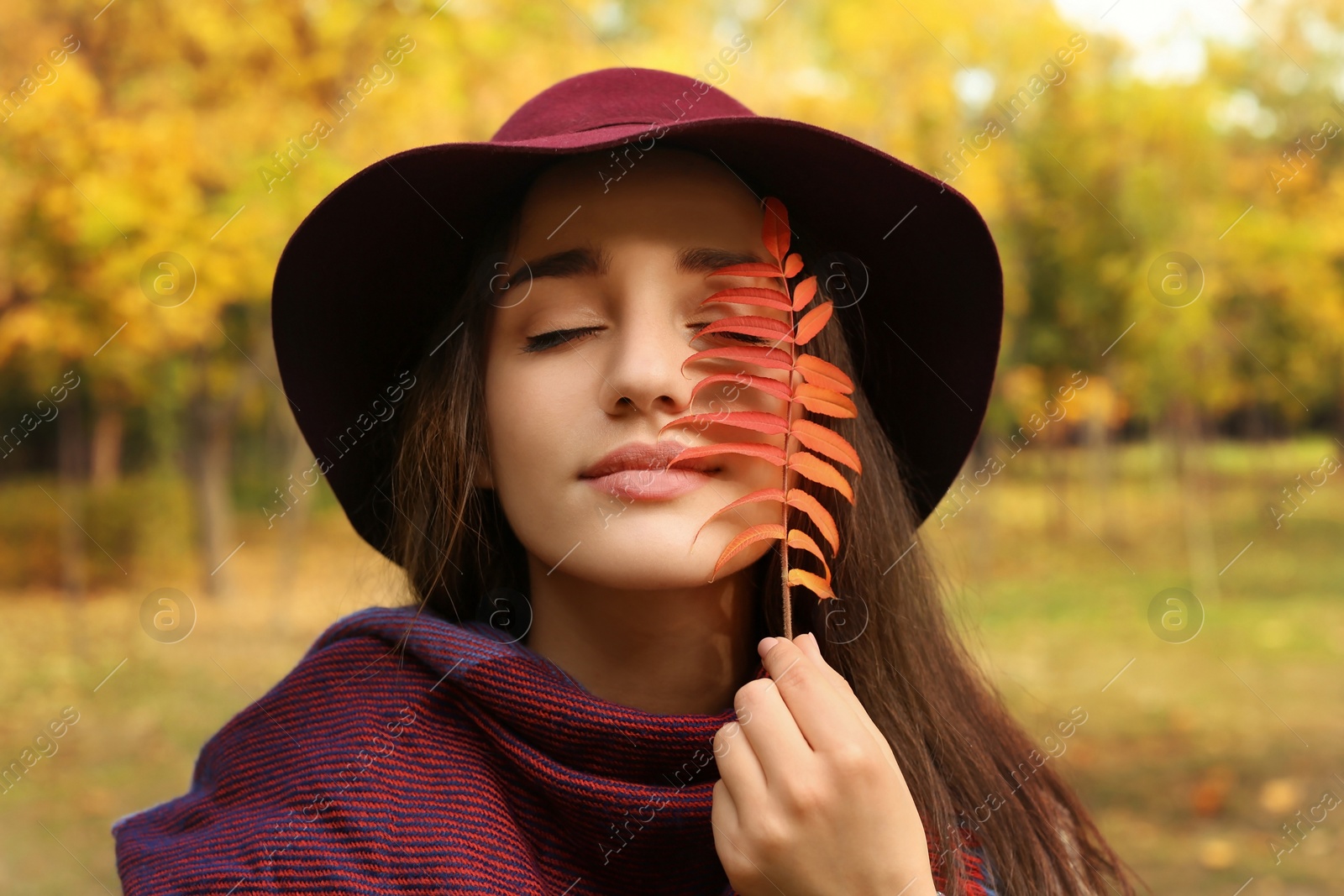 Photo of Young beautiful woman with hat and leaf in park. Autumn walk