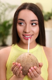 Photo of Young woman with fresh coconut at home. Exotic fruit