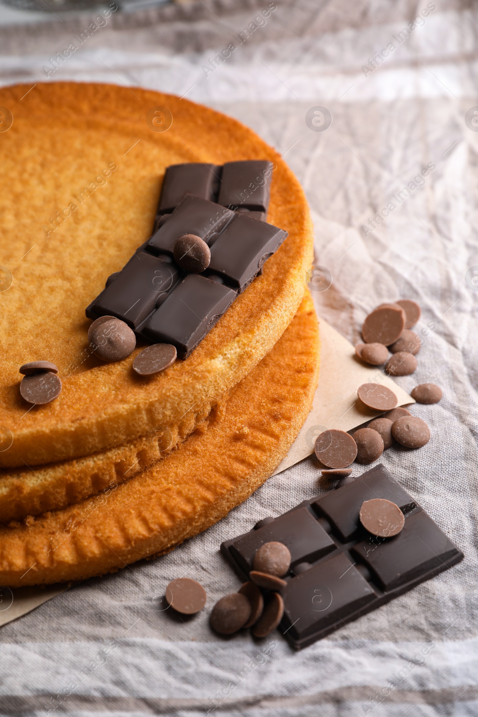 Photo of Delicious homemade sponge cakes and different types of chocolate on grey tablecloth, closeup