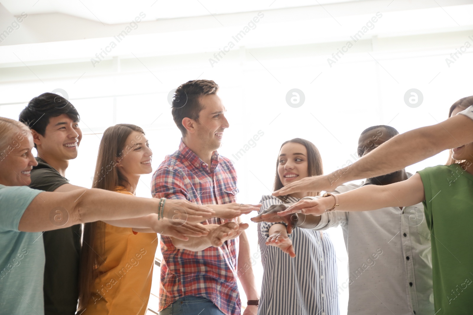 Photo of People putting hands together indoors. Unity concept