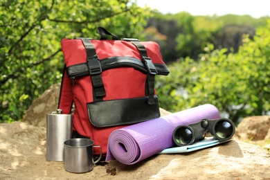 Photo of Modern backpack and camping equipment on large rock in wilderness