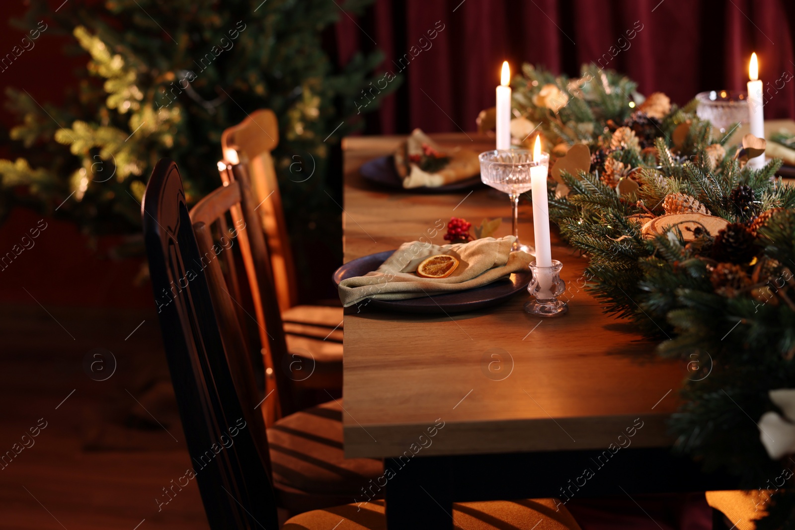 Photo of Dining table with burning candles and Christmas decor in stylish room. Interior design