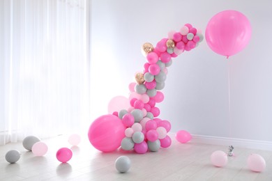 Image of Balloon garland near white wall in room. Festive decor