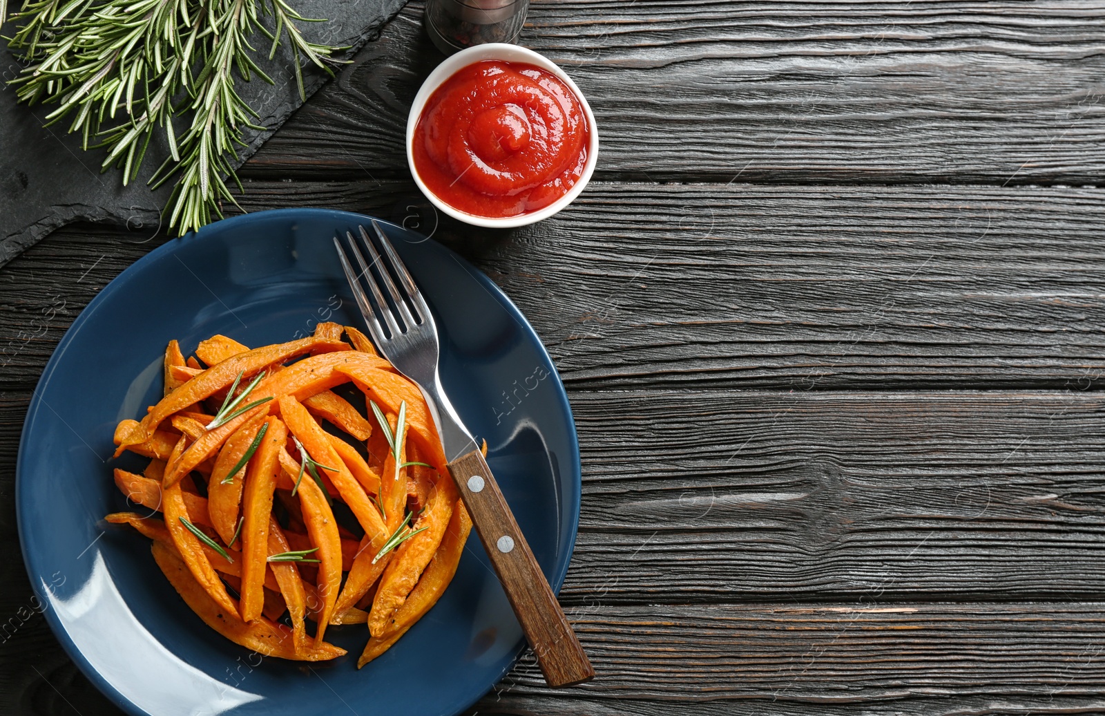 Photo of Plate with tasty sweet potato fries on wooden table, flat lay. Space for text