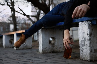 Photo of Addicted drunk man with alcoholic drink lying on bench outdoors, closeup