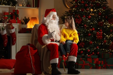Photo of Merry Christmas. Little girl with Santa Claus in room