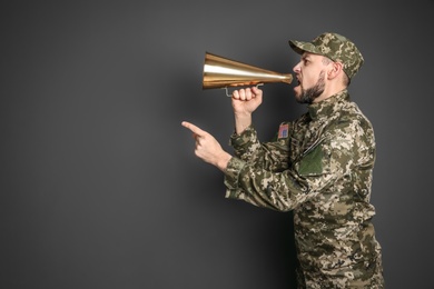 Photo of Military man shouting into megaphone on gray background