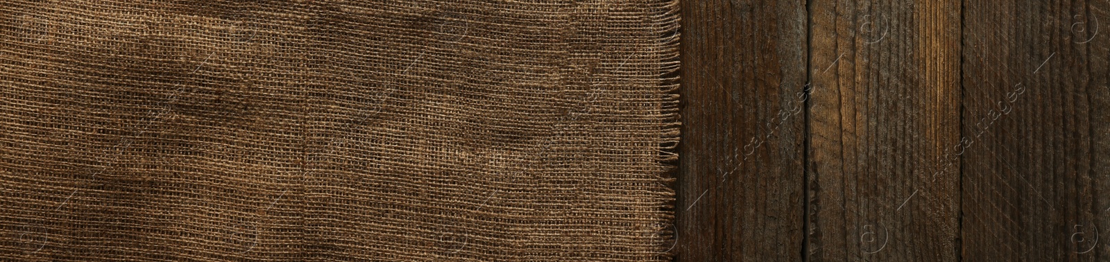 Photo of Burlap fabric on wooden table, top view. Space for text