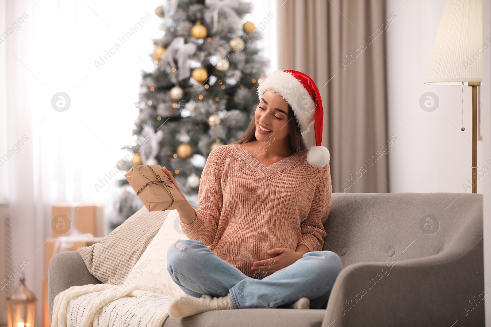 Photo of Happy pregnant woman with Christmas gift box at home. Expecting baby