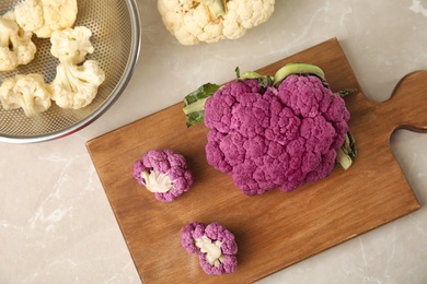 Wooden board with purple cauliflower cabbage on table, top view. Healthy food