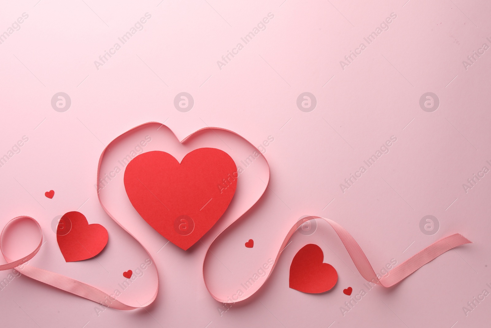 Photo of Paper hearts and ribbon on pink background, flat lay. Space for text