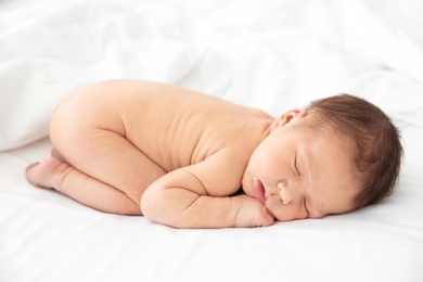 Adorable newborn baby sleeping on bed