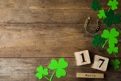 Flat lay composition with clover leaves and block calendar on wooden background, space for text. St. Patrick's day
