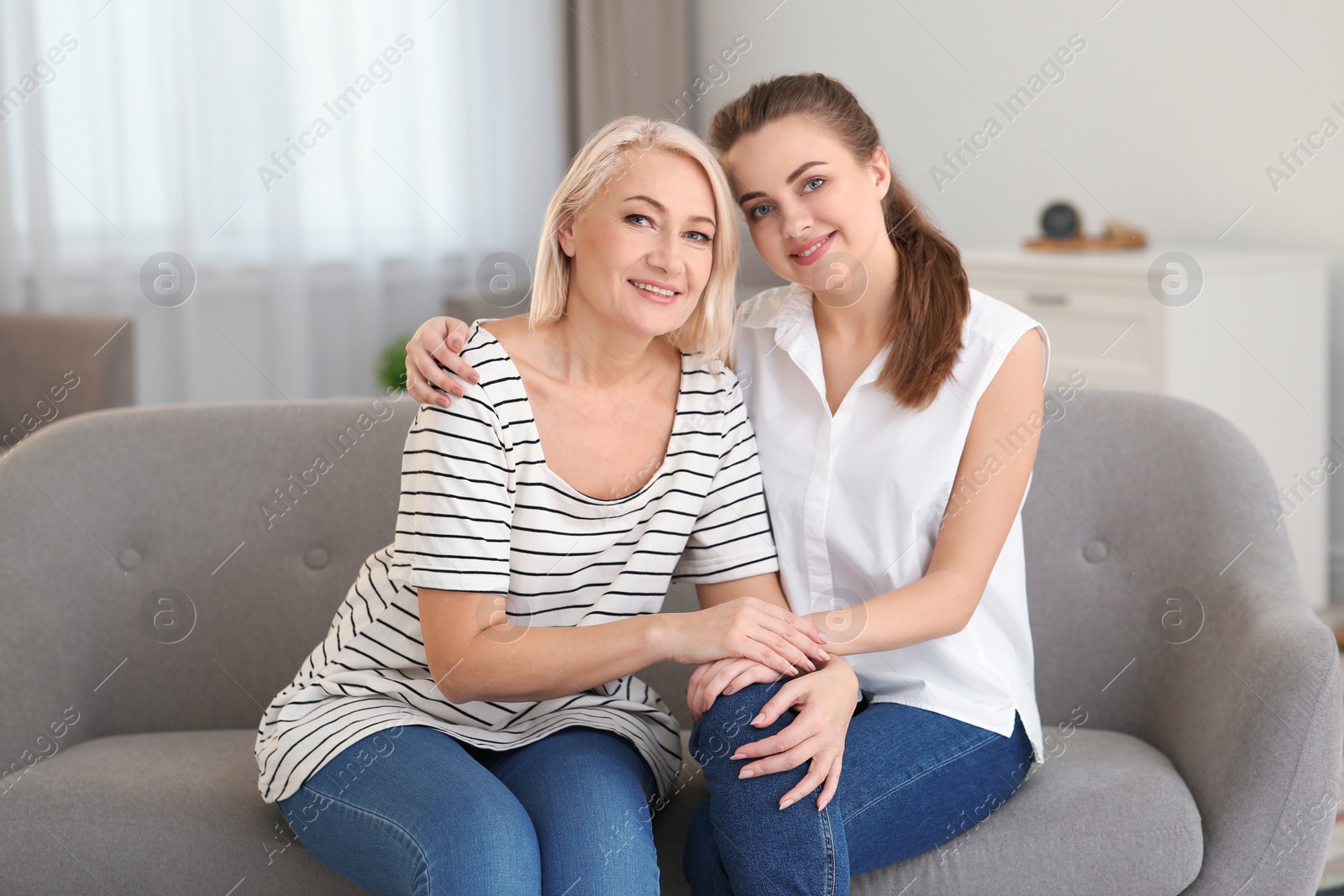 Photo of Portrait of mature woman and her daughter on sofa in living room