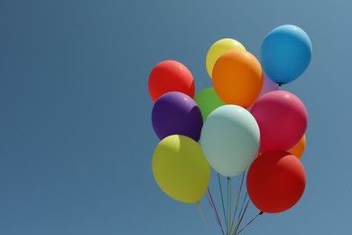 Photo of Bunch of colorful balloons against blue sky. Space for text