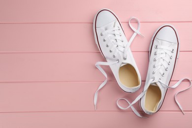 Photo of Pair of white sneakers on pink wooden table, flat lay. Space for text