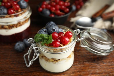 Delicious yogurt parfait with fresh berries and mint on wooden table, closeup