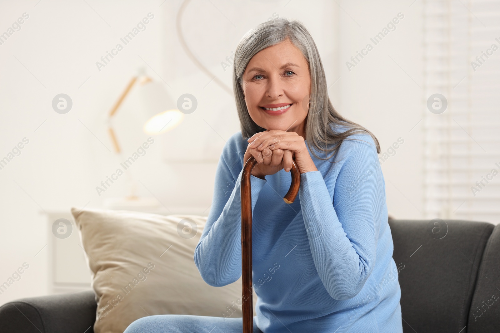 Photo of Mature woman with walking cane on sofa at home